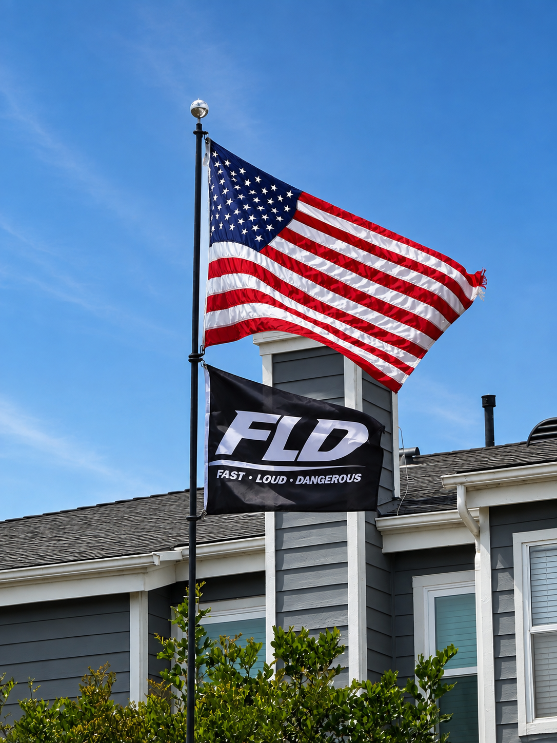 FLD black logo flag flying below an American flag outdoors