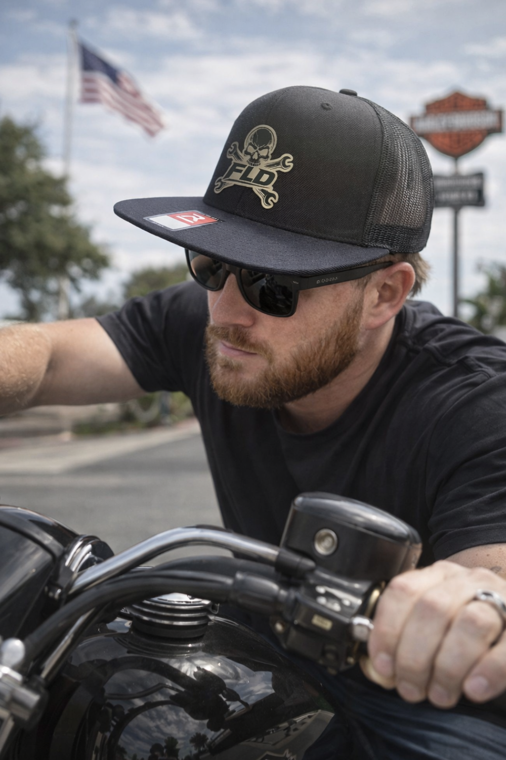 Man on a motorcycle wearing a black cap and sunglasses with a blurred background